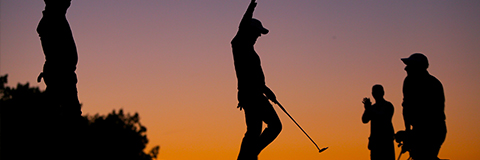 Silhouettes of several golfers in sunset light.